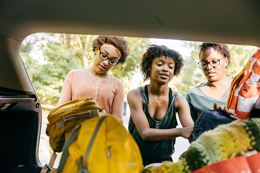 African family consisting of two daughters and their mom, packing their equipment for their road trip together.