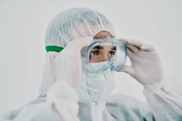 It's what modern heroes wear Shot of a young man putting on his protective gear before the decontamination process contamination stock pictures, royalty-free photos & images