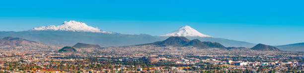 Iztaccihuatl and Popocatepetl volcanoes and Mexico City Panoramic stock photo of the snow covered Iztaccihuatl aka Ixtaccihuatl (left) and Popocatepetl (right) volcanic mountains with Mexico City at their feet as seen from Mexico City, Mexico. dormant volcano stock pictures, royalty-free photos & images