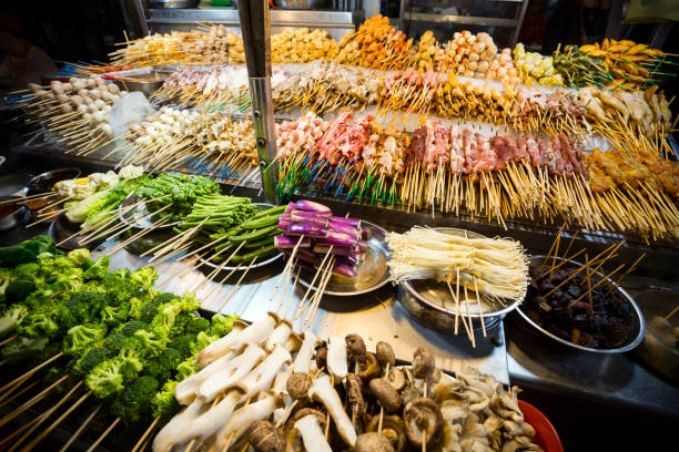 Jalan Alor Lok-Lok Malaysian Cuisine Lok-lok is a dish consisting of various deep-fried foods and raw foods such as meats and vegetables that are served on a skewer. The skewers are dipped in boiling water to cook then dipped in a sauce and eaten. It is a popular street food throughout Malaysia. bukit bintang stock pictures, royalty-free photos & images