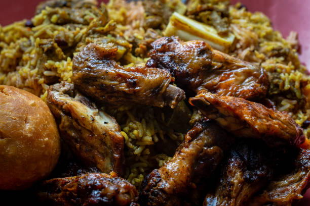 Jamaican jerk chicken wings, curried goat and fried dumpling with rice and peas stock photo
