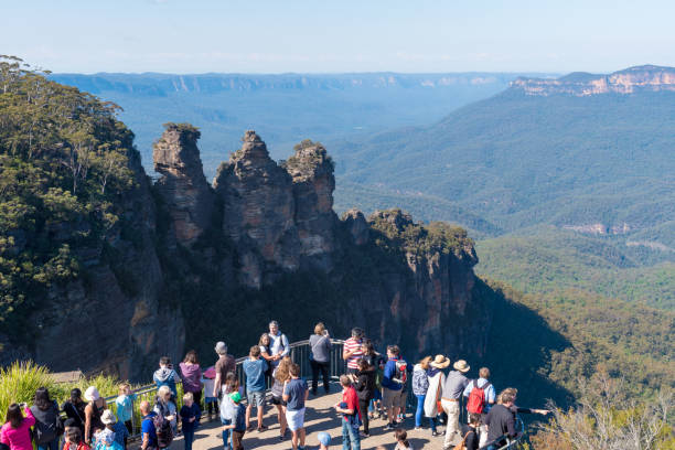 Jamison Valley and Three Sisters rock formation in Katoomba, Australia Katoomba, Australia- April 15, 2017: View towards Jamison Valley and Three Sisters rock formation from Echo Point lookout and tourists in Katoomba, Blue Mountains, New South Wales, Australia. anchor point stock pictures, royalty-free photos & images