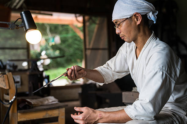 Japanese blacksmith inspecting the quality of a knife blade stock photo