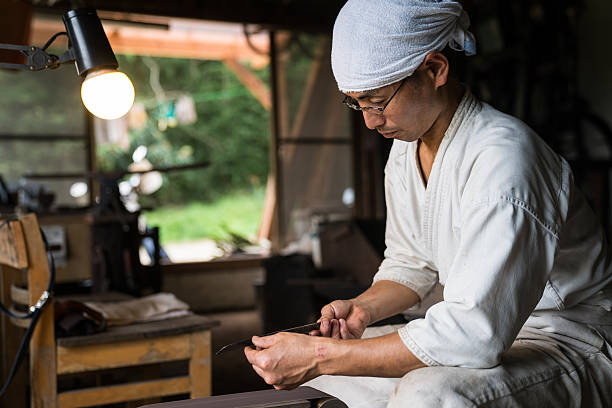 Japanese blacksmith inspecting the quality of a knife blade stock photo