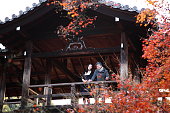 京都・トフクジの橋の上で紅葉を楽しむ日本のカップル