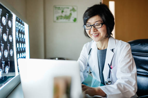 Japanese Doctor Using Computer And Looking At X-rays stock photo
