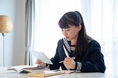 居間でオンラインで勉強している日本人女子高生