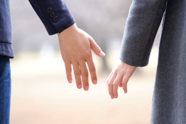 A Japanese man and woman holding hands in a park in winter A Japanese man and woman holding hands in a park in winter shy japanese woman stock pictures, royalty-free photos & images