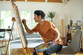 istock Japanese man spending weekend morning painting in his bedroom at home 1321486723