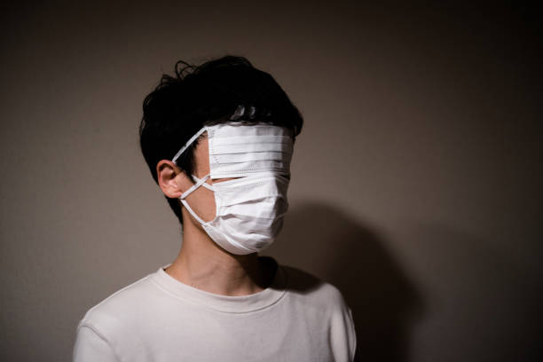 A Japanese man wearing a surgical mask is standing stock photo