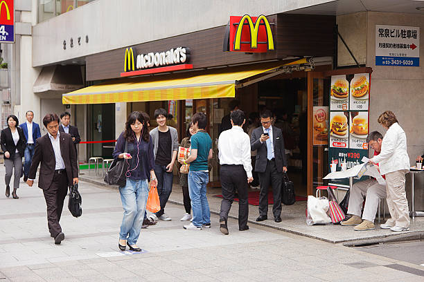 Japanese McDonald's Restaurant Tokyo, Japan - May 31, 2011: People walk on the sidewalk in front of a McDonald's restaurant in the Hamamatsucho business district of Minato Ward in Tokyo. McDonald's has over 3,500 locations in Japan. mcdonalds japan stock pictures, royalty-free photos & images