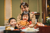 日本の部屋の食卓で、お飾ちりり、日本の新年料理を食べる日本人の母子