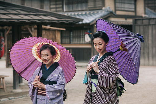 Three Japanese women in traditional kimonos walking in Edo period town.