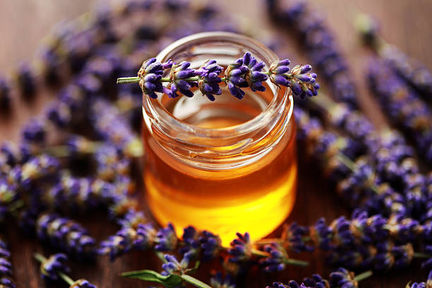 Jar of herbal honey surrounded by lavender flowers stock photo