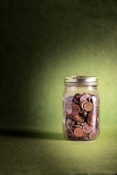 Jar of pennies on green background (Money Series) stock photo
