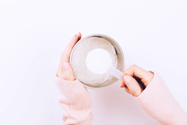 A jar with collagen powder and scoop spoon in woman hands. A jar with collagen powder and scoop spoon in woman hands. Flat-lay, top view. collagen stock pictures, royalty-free photos & images