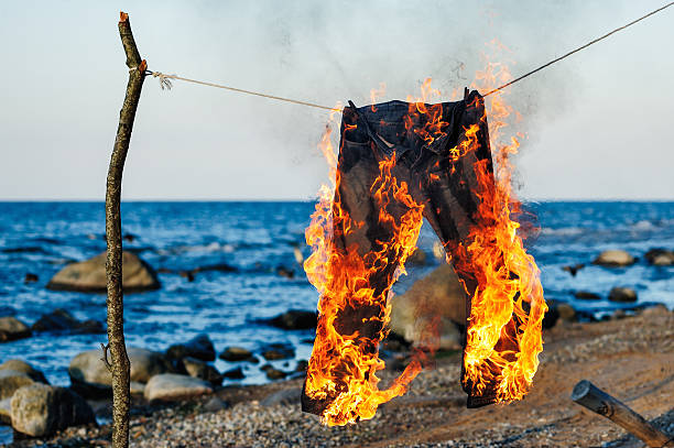 Jeans burning Pants burning on a rope on a seashore pants stock pictures, royalty-free photos & images