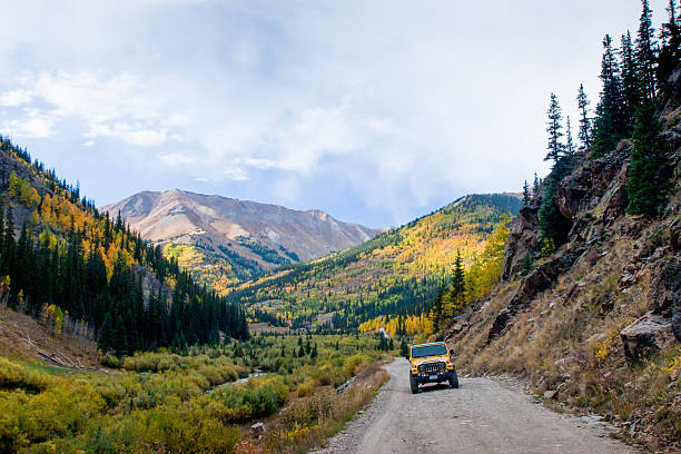 Jeep on the road Yellow Jeep on Cinnamon Pass in autumn, Colorado. 4x4 stock pictures, royalty-free photos & images