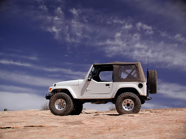 Jeep Wrangler on top of a sand dune Jeep off road vehicle at the edge of a red rock cliff near Moab, Utah. off road vehicle stock pictures, royalty-free photos & images