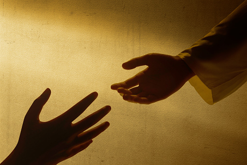 Jesus Christ giving a helping hand to human with wall background