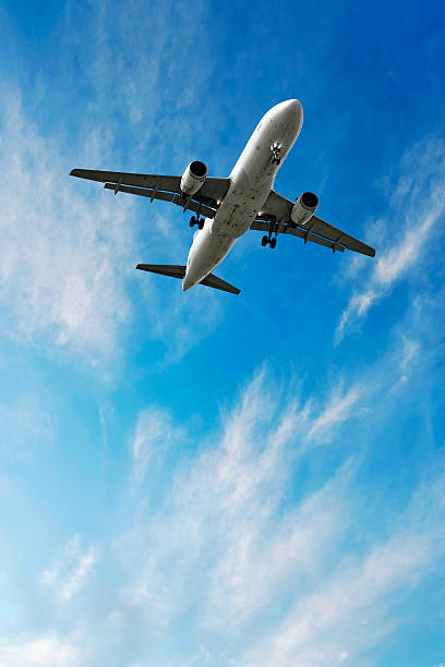 jet airplane landing in bright sky stock photo
