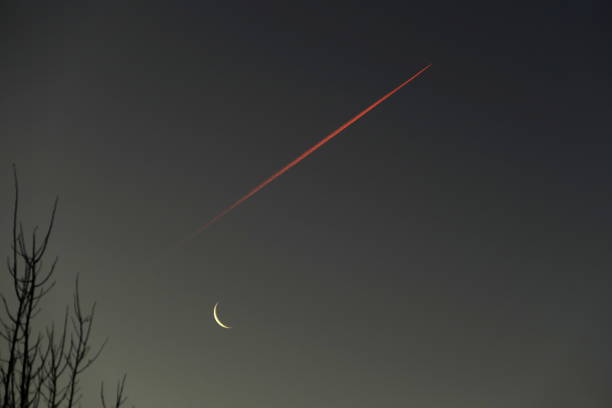 Jet Stream with waning crescent moon at Sunrise. Bavaria, Germany. stock photo