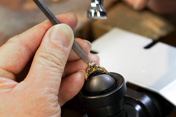 Jewelry Repairing A Jeweller is Repairing a Diamond Ring & setting a Diamond on the Ring with Motion Blur on the Hammer. gold ring on finger stock pictures, royalty-free photos & images