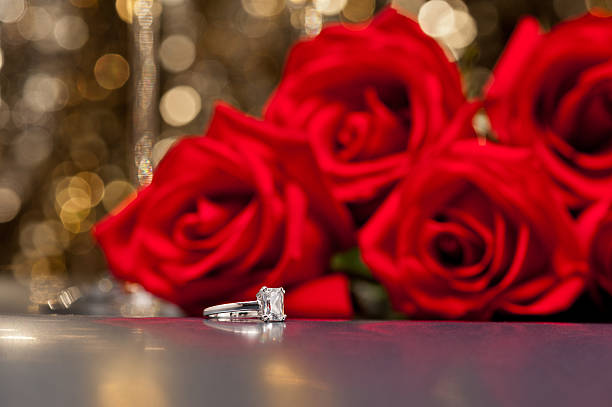 Jewelry ring and roses in front of a gold glitter background