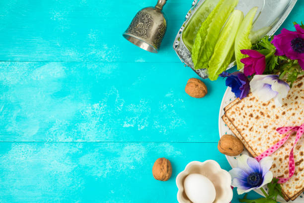 Jewish holiday Passover background with matzo, seder plate and spring flowers on wooden table. Jewish holiday Passover background with matzo, seder plate and spring flowers on wooden table. Top view from above. passover stock pictures, royalty-free photos & images