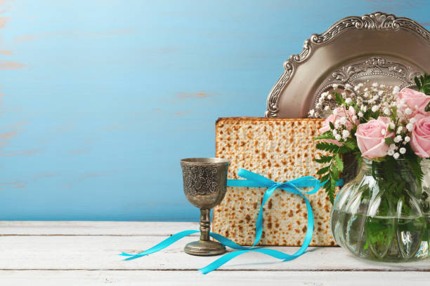 Jewish holiday Passover Pesah background with matzoh, rose flowers and wine glass on wooden table with copy space Jewish holiday Passover Pesah background with matzoh, rose flowers and wine glass on wooden table with copy space passover stock pictures, royalty-free photos & images