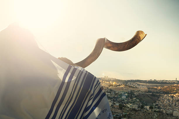 Jewish man blowing the Shofar with view of the holy city of Jerusalem