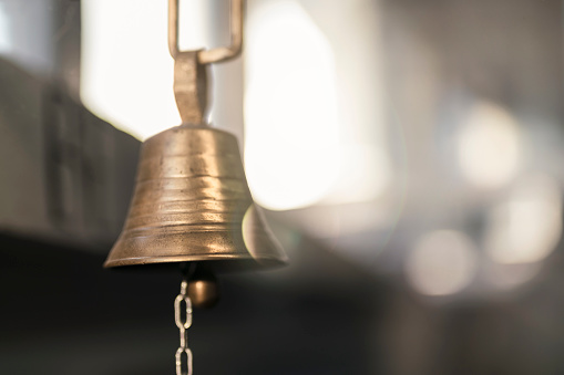 Close up of a metal bell hanging from the wall