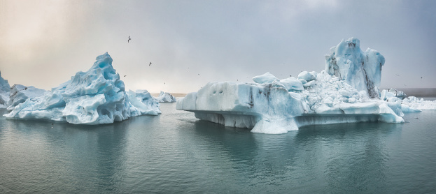 Iceland Jökulsarlon Glacier Lagoon Panorama. View to the drifting Icebergs on the natural glacier lake lagoon of Jökulsarlon in moody and foggy sunset twilight light. Jokulsarlon, Drone Flight Point of View. Vatnajökull National Park, Route 1, Southeast Iceland, Iceland, Nordic Countries, Northern Europe