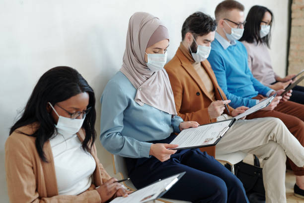 Job candidates in masks examining resume before interview stock photo