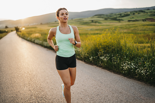 One young sporty woman jogging in nature at beautiful summer sunset