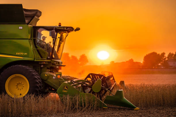 John Deere S670 Soybean Sunset Henry County, Ohio - September 25, 2020: A profile view of a John Deere S670 harvesting soybeans during a hazy sunset with a red and orange sky from the bean dust. agricultural equipment photos stock pictures, royalty-free photos & images