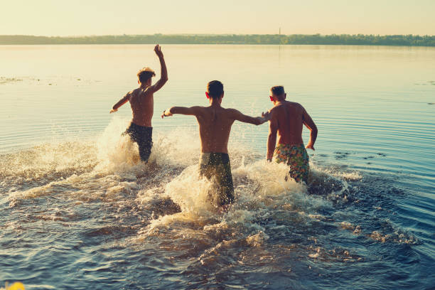 Joyful friends run into the water in a cloud of spray stock photo