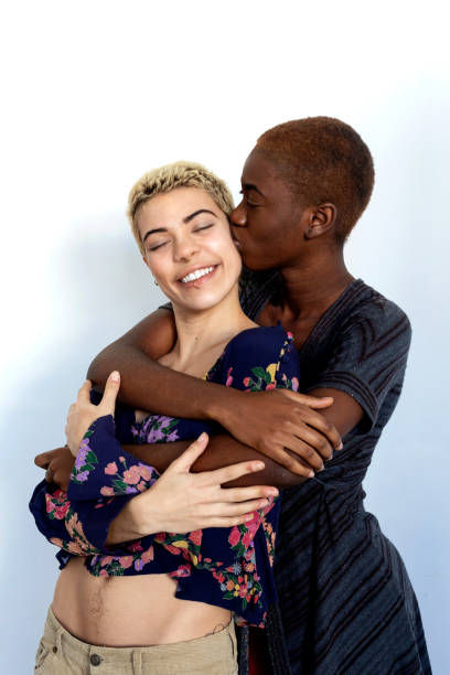 Joyful ladies kissing and embracing togetherness, being of different of races, dressed in casual clothes. stock photo