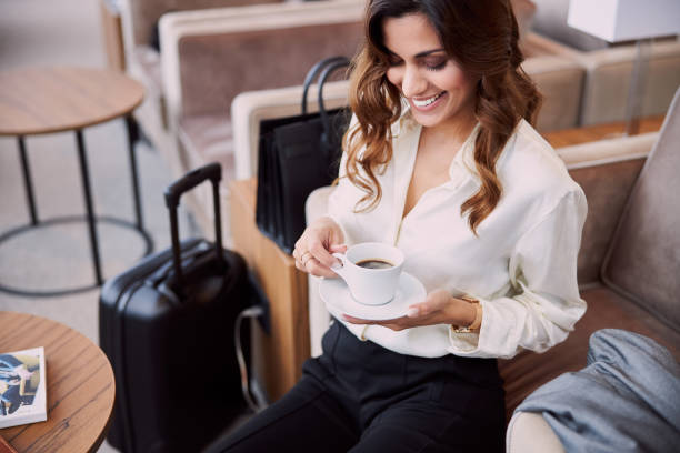 joyful lady drinking coffee in airport departure lounge - airport lounge imagens e fotografias de stock