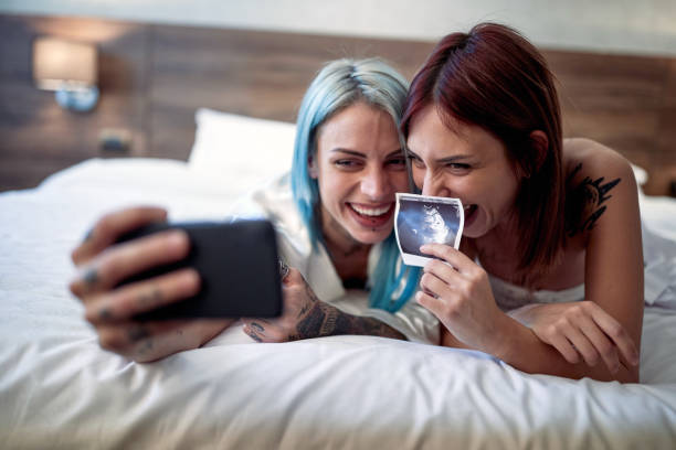 Joyful lesbian couple announcing a pregnancy test results stock photo