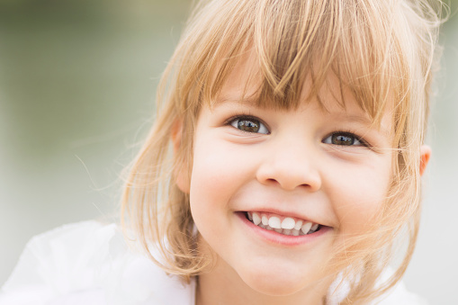 Beautiful close-up child portrait of smiling joyful blond hair little girl.