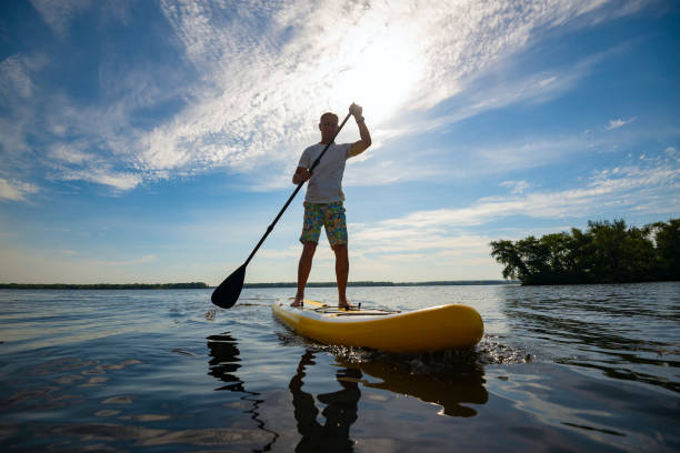 Joyful man paddling on a SUP board stock photo