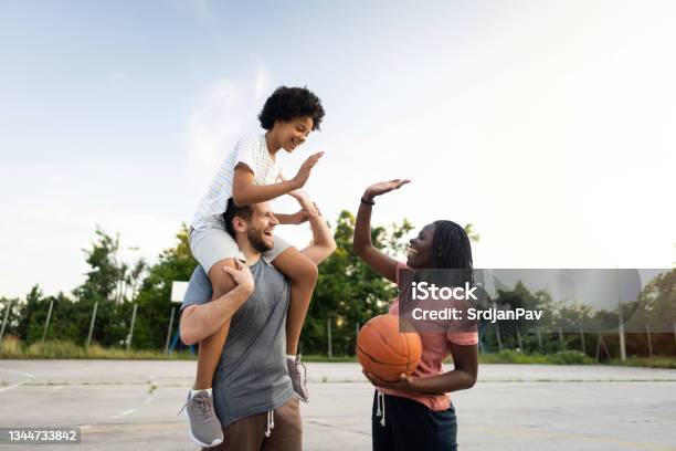 Joyful multiracial stepfamily interchange high-five after their basketball game
