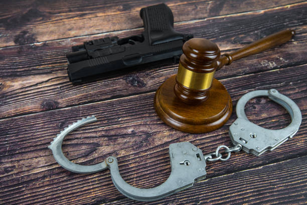 Judge gavel, pistol and handcuffs on wooden background.