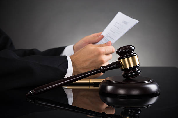 Judge Holding Document At Desk Close-up Of Judge Holding Document With Gavel At Desk sentencing stock pictures, royalty-free photos & images