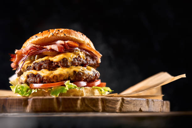 Juicy burger on the board, black background. Dark background, fast food. Traditional american food. Copy space Juicy burger on the board, black background. Dark background, fast food. Traditional american food. Copy space cheeseburger stock pictures, royalty-free photos & images