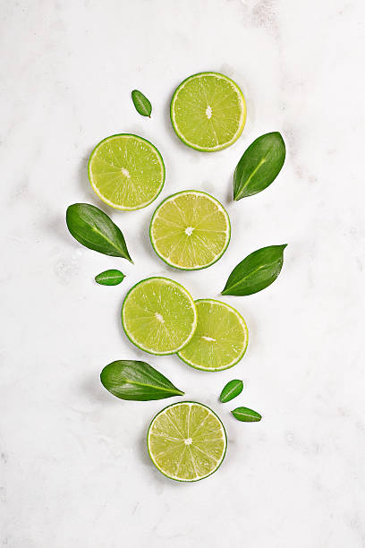 Juicy lime slices flat lay on marble background. Top view stock photo
