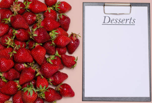 Juicy, ripe strawberries are laid out on a pink background with a tablet for recording dessert. Copy Space. Juicy, ripe strawberries are laid out on a pink background with a tablet for recording dessert. Copy Space planchette stock pictures, royalty-free photos & images
