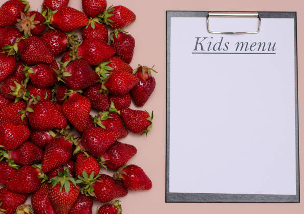 Juicy, ripe strawberries are laid out on a pink background with a tablet for recording the Copy Space children's menu. Juicy, ripe strawberries are laid out on a pink background with a tablet for recording the Copy Space children's menu planchette stock pictures, royalty-free photos & images