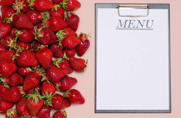 Juicy, ripe strawberries are laid out on a pink background with a tablet for recording the menu. Copy Space. Juicy, ripe strawberries are laid out on a pink background with a tablet for recording the menu. Copy Space planchette stock pictures, royalty-free photos & images